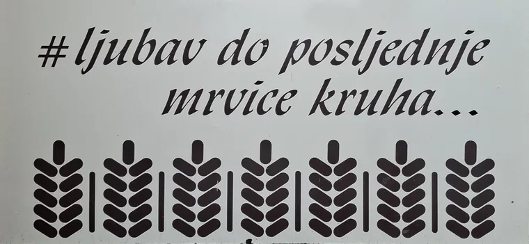 Bijela ploča s natpisom #ljubav do posljednje mrvice kruha i nizom klasja